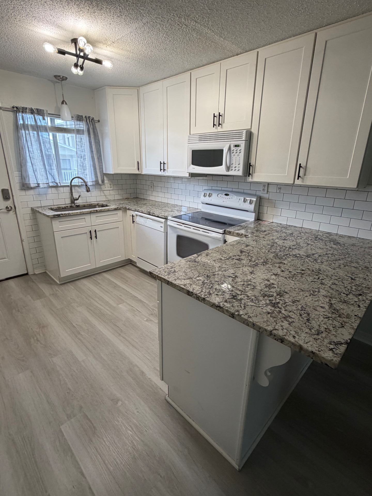 Freshly cleaned kitchen with white cabinets and granite countertops