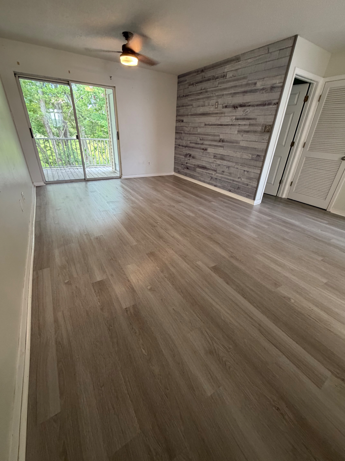 Freshly cleaned empty living room with wood accent wall and balcony view
